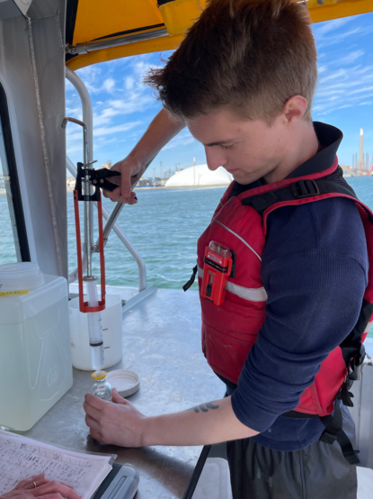 Technician filtering water sampled on a boat using a caulking gun.