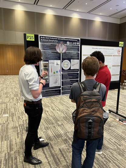 A group of 3 people looking at a scientific poster 