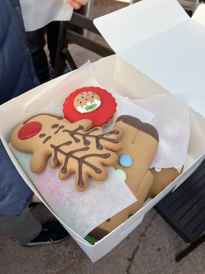 A box of Christmas themed biscuits. A reindeer face is on the top biscuit. 
These were brought in by one of our lovely volunteers. 