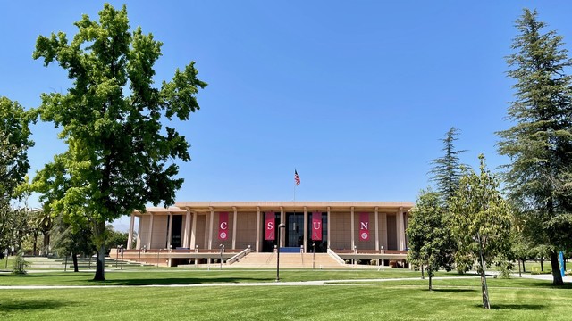 A view across the CSUN campus quad to the University Library, a wide midcentury structure that recalls an abstracted Egyptian or maybe Greek temple with a wide staircase leading up to a portico that stretches across the whole facade