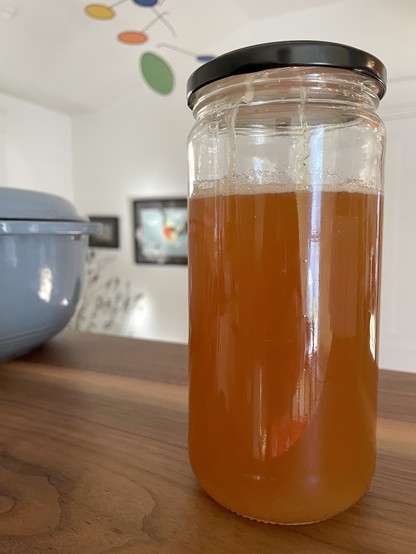 Closeup of a 6 ½ inch high glass jar filled about 4/5 of the way with maple syrup. The syrup is a caramel/amber color and if you look closely there are sugar streaks on the inside where the crystallized syrup stuck to the glass.