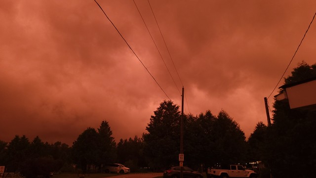 A menacing, dark yellow-orange sky illuminates the ground at a campground during a severe thunderstorm.