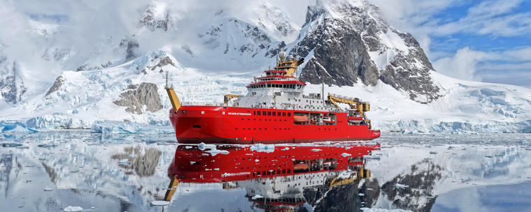 image/jpeg a large red and white research ship floats in calm waters which reflect the rugged, icy, mountainous coast of Antarctica. The RRS Sir David Attenborough, British Antarctic Survey.
